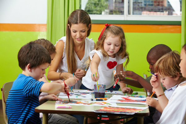 Kinder malen mit Erzieherin im Kindergarten